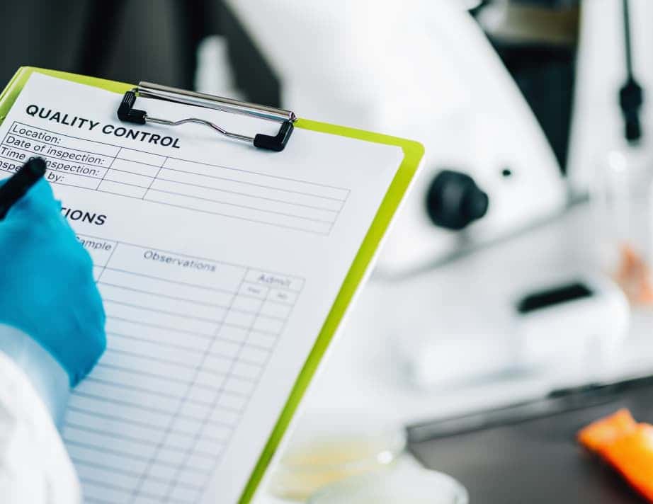 close-up of employee writing quality control on clipboard